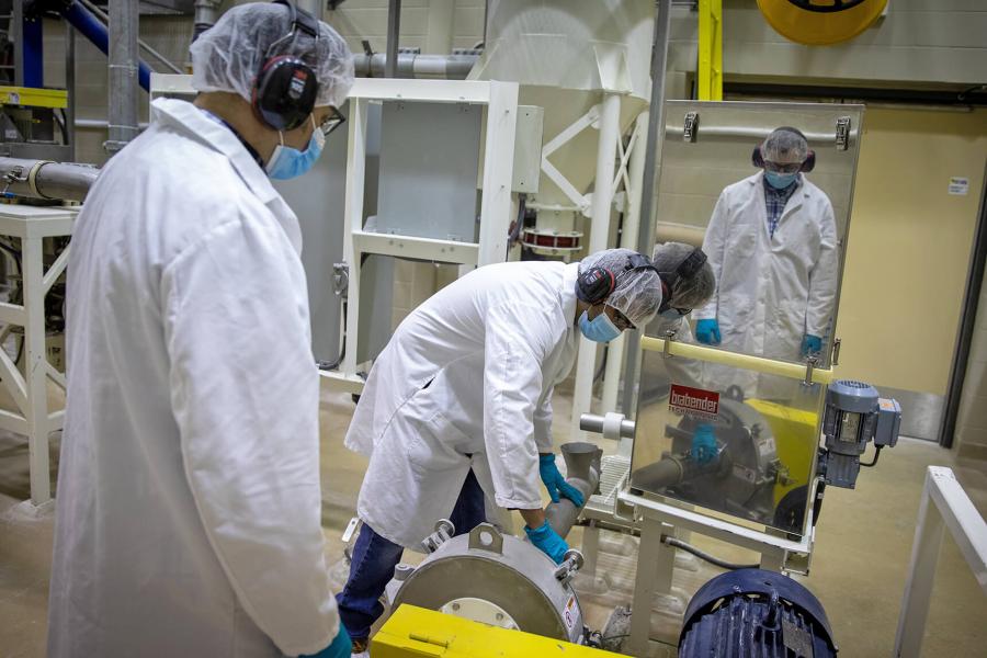 Two technicians operate the milling equipment.